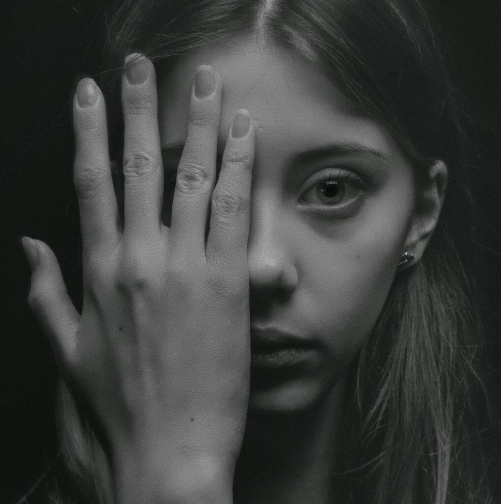 grayscale photo of woman covering her face by her hand - stress