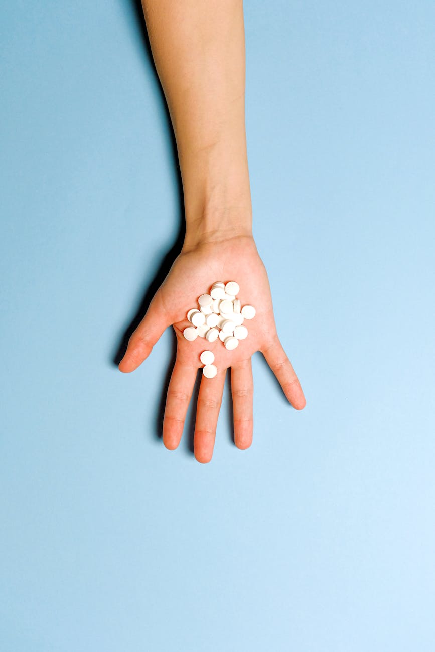 person holding white round medication pills - insomnia melatonin