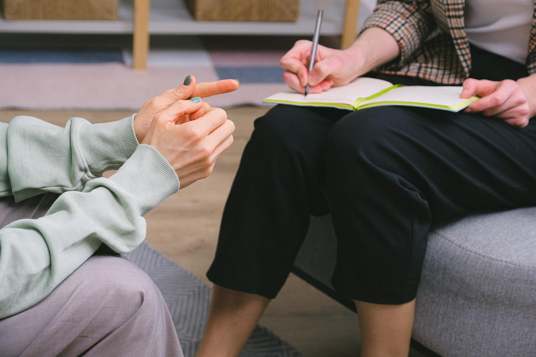 anonymous female therapist and client sitting in armchairs during session in modern office - stress 