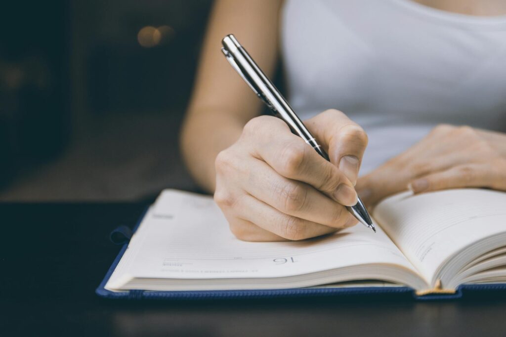 photo of person writing on notebook 